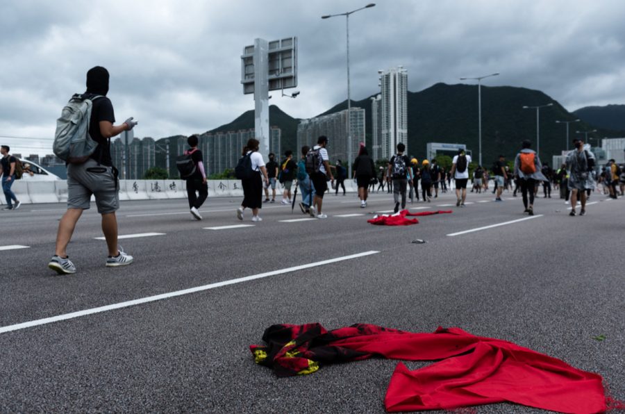 Protestors walk past defaced Chinese flags.
