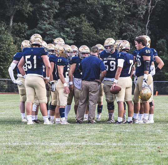 Salesianum football players huddling up around Coach DiNardo.