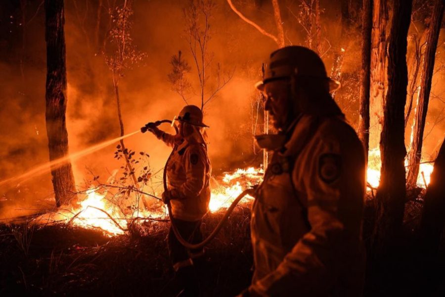 Two Australian firefighters work to quell the raging flames around them.